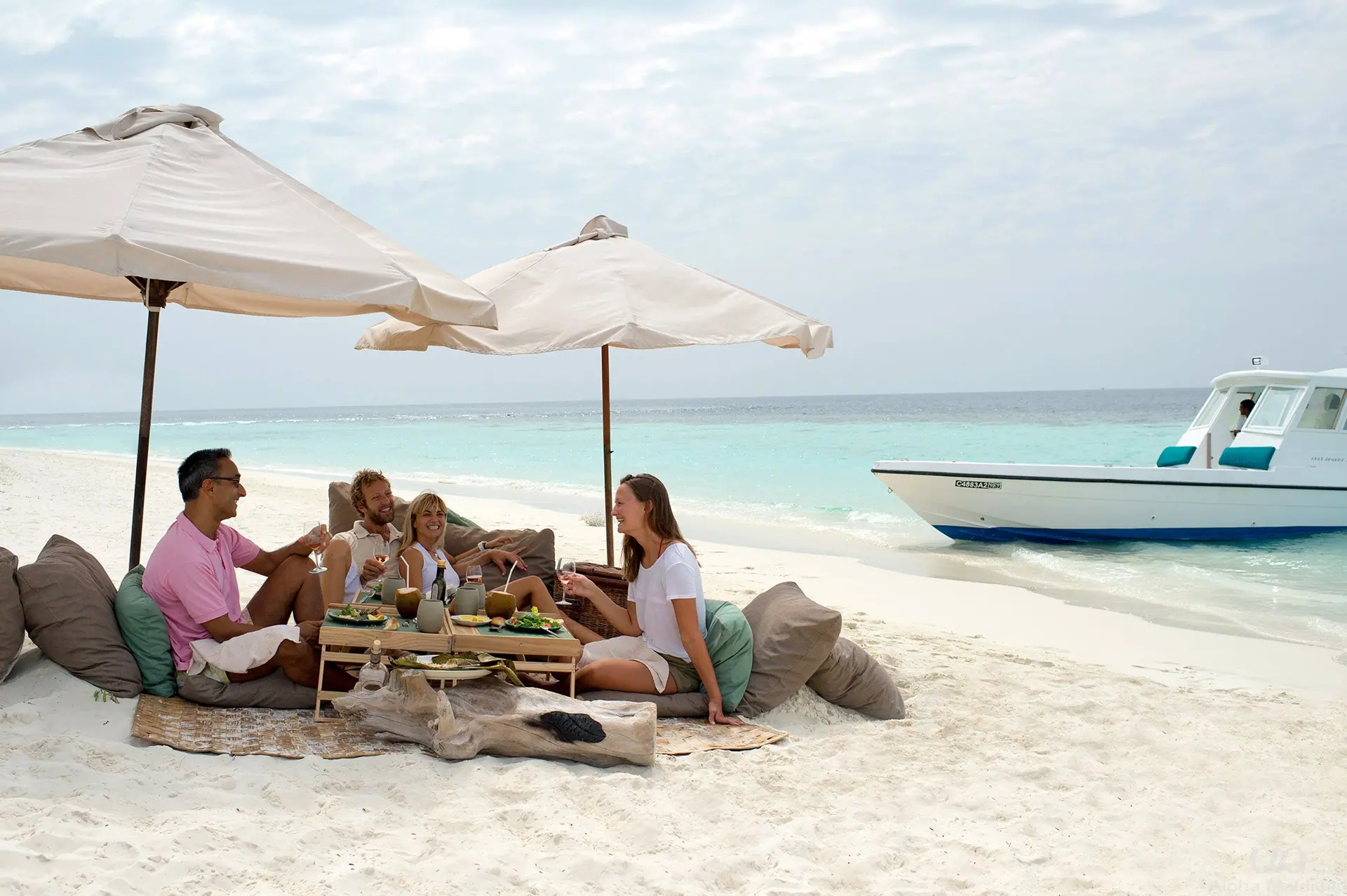 Travellers sharing a shaded lunch on a beach beside their boat