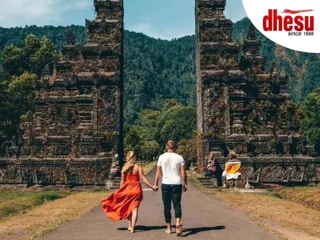 A couple in covered-up clothing walking up to a stone temple gateway