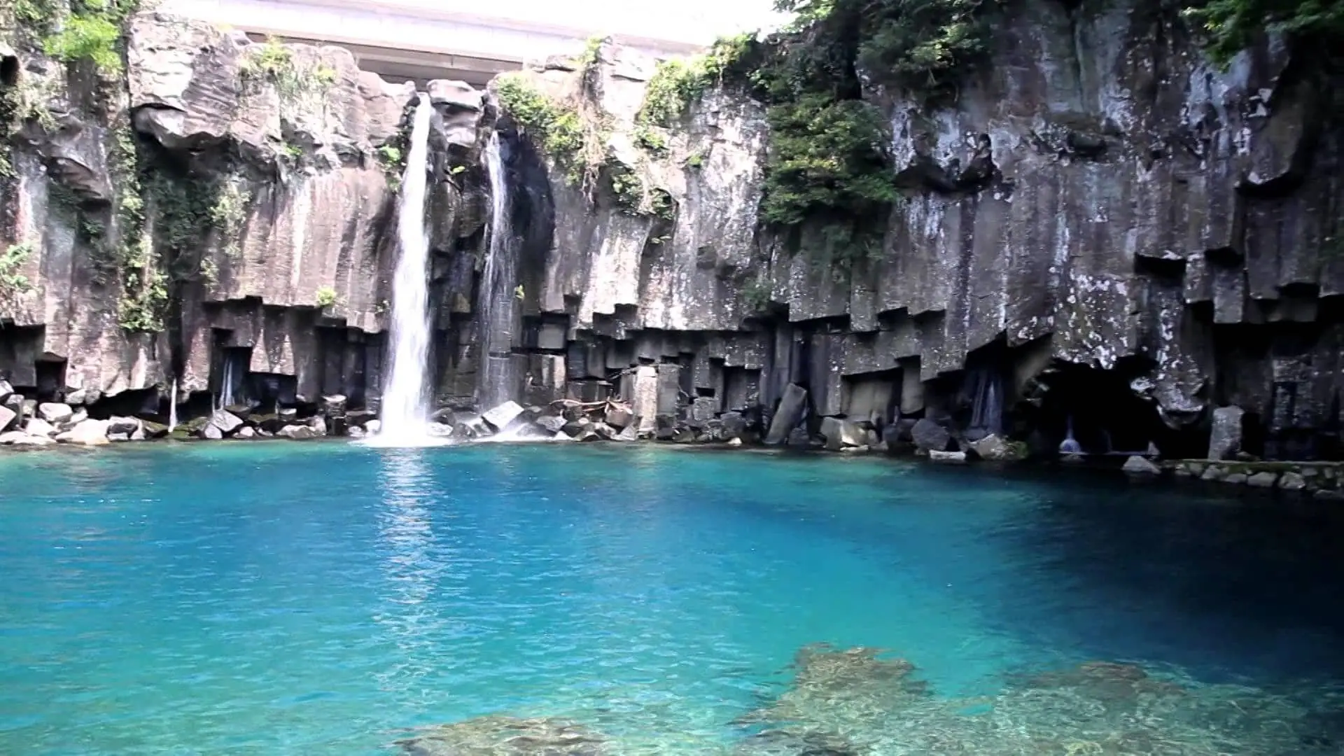 A waterfall dropping into a pool below a wall of basalt columns