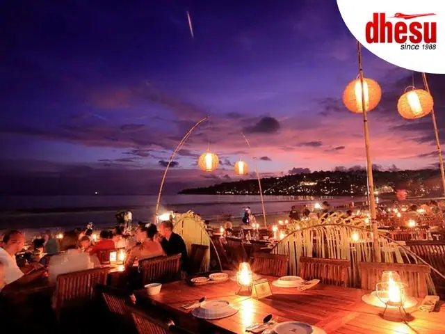 Grilled seafood dinner laid on tables at Jimbaran Bay beach at sunset, Bali