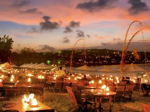 Candlelit tables set out along the sand at dusk in Bali