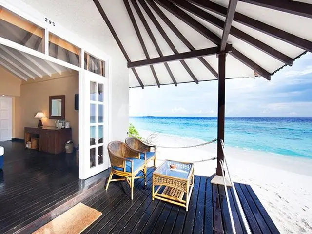 A shaded villa deck opening onto a quiet beach